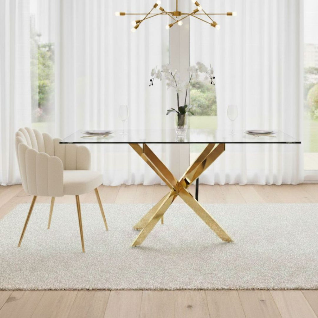 Dining room with a glass table and gold legs, white chairs, and large windows.